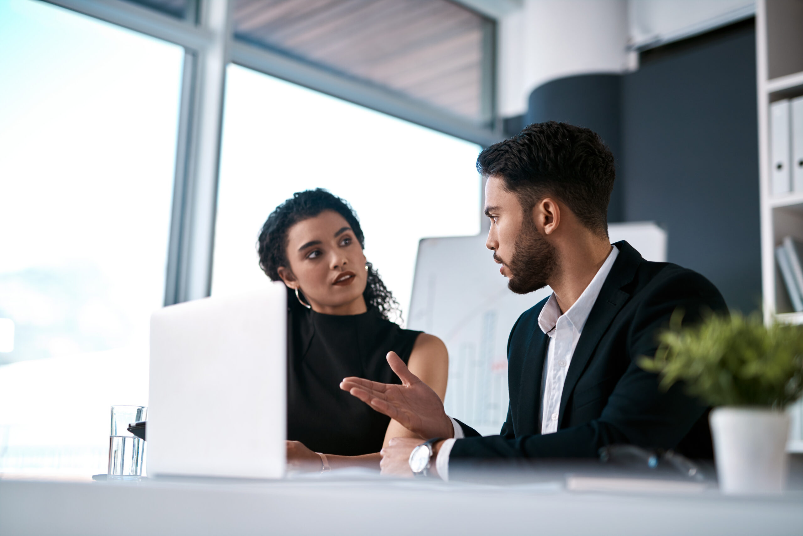 A professional discussing business development opportunities with a teammate in the office.