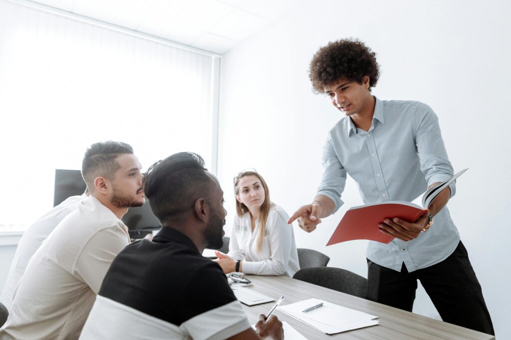 Ambitious professional participating in leadership development while guiding a team meeting in a business office.